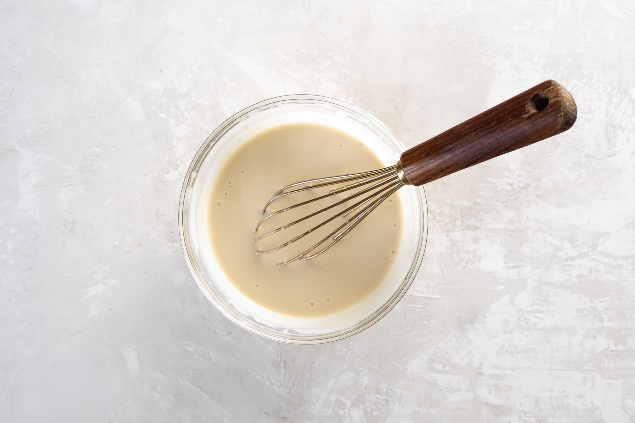 Best easy homemade Tahini Sauce recipe! This Middle Eastern sauce is made with tahini (sesame seed paste), garlic and lemon juice. It's creamy, tangy and bright, with a slight nutty flavor. Drizzle this vegan sauce over salads, roasted vegetables, falafel, a Buddha Bowl, and more! Tahini sauce in a small mixing bowl with a whisk.